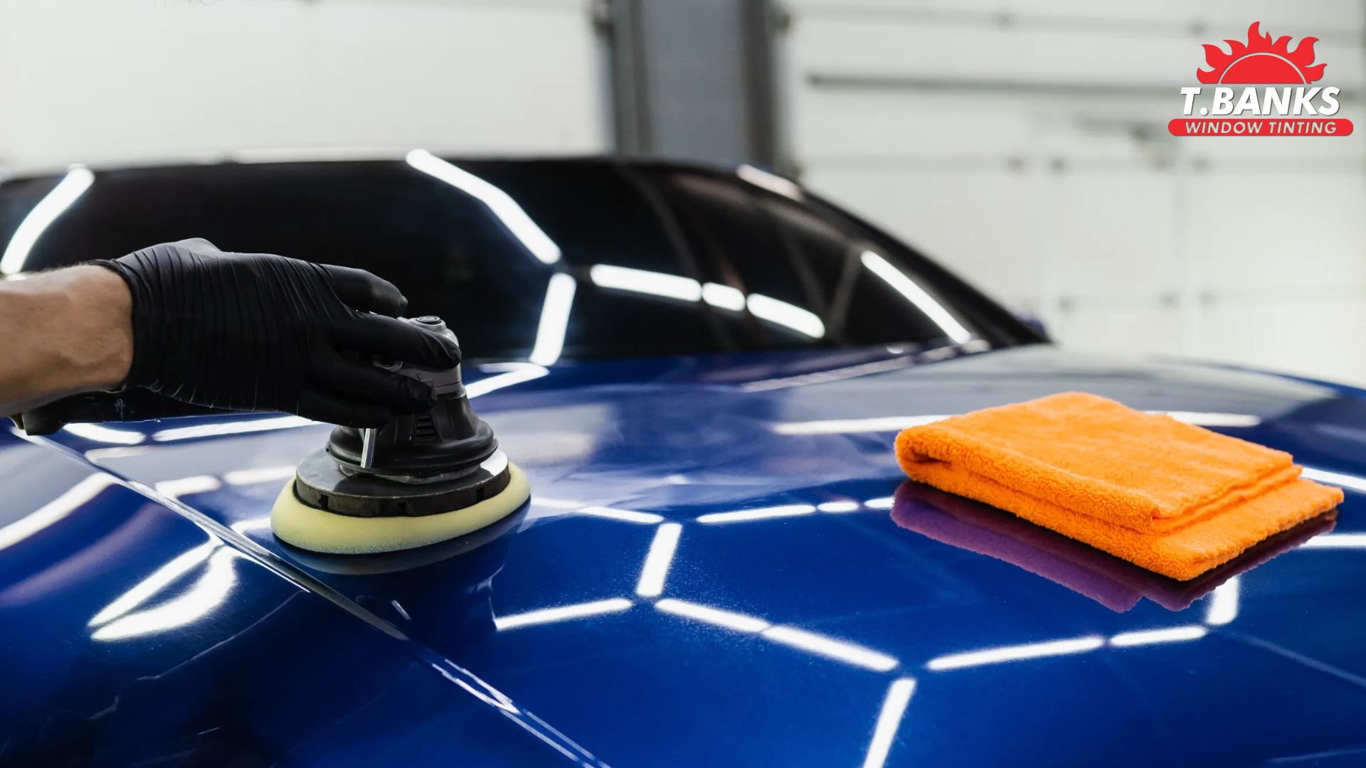 A technician uses a polisher on the hood of a blue car, with an orange microfiber towel resting nearby. T.Banks Window Tinting logo is visible in the corner.