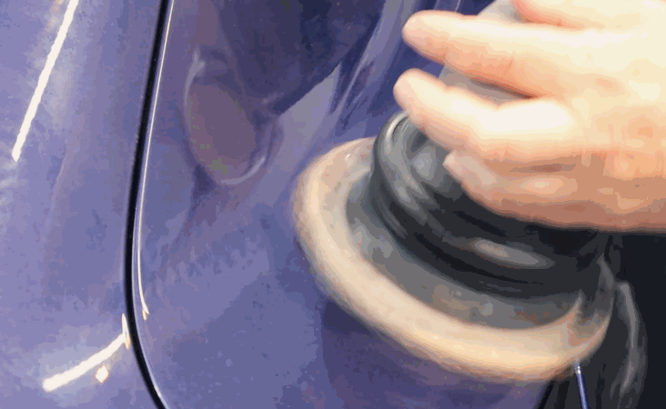 A polisher is used on a purple car panel to remove surface imperfections before ceramic coating.