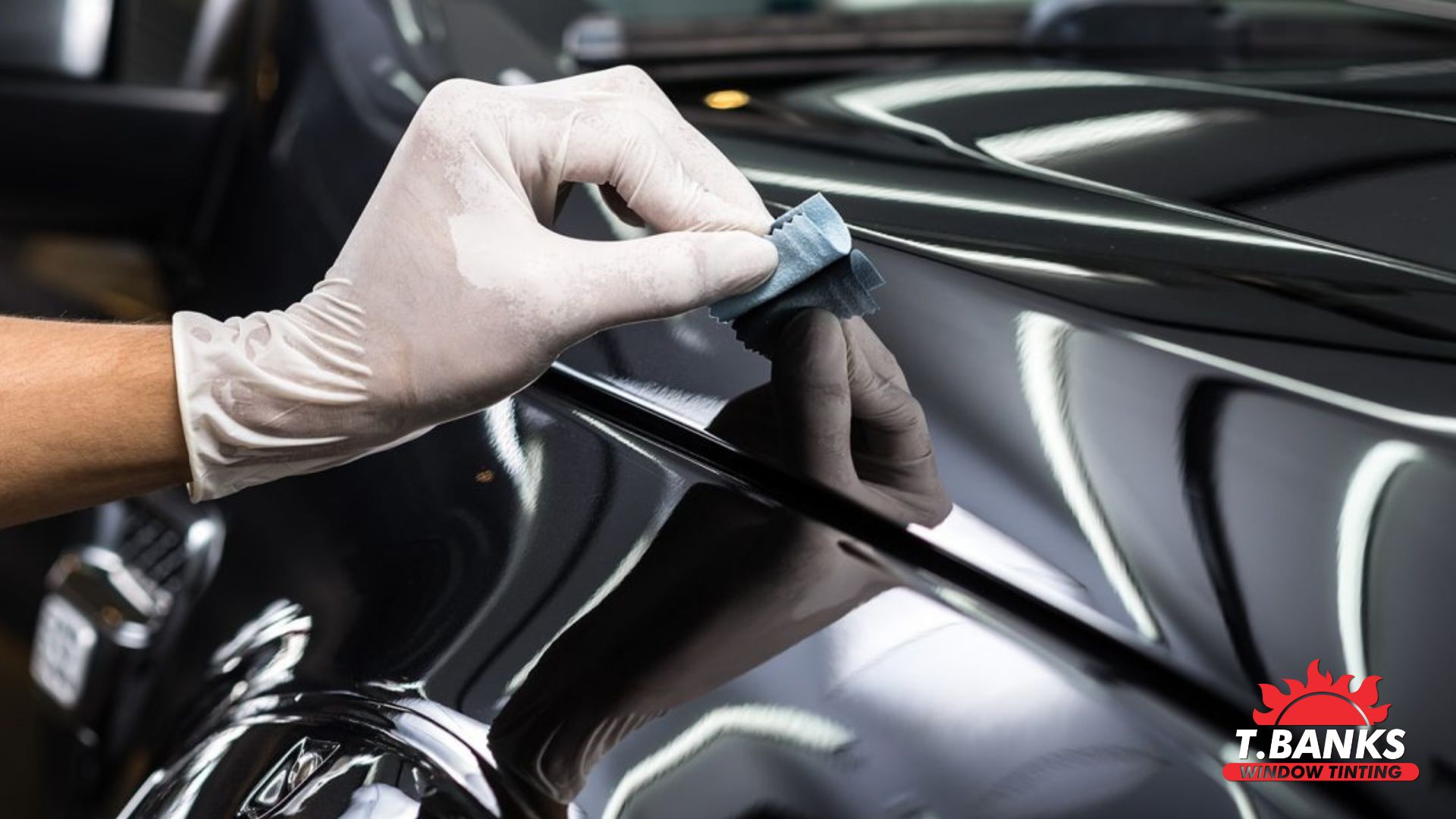 A gloved hand applies ceramic coating to a black car’s surface with a suede applicator cloth. The T. Banks Window Tinting logo is visible.