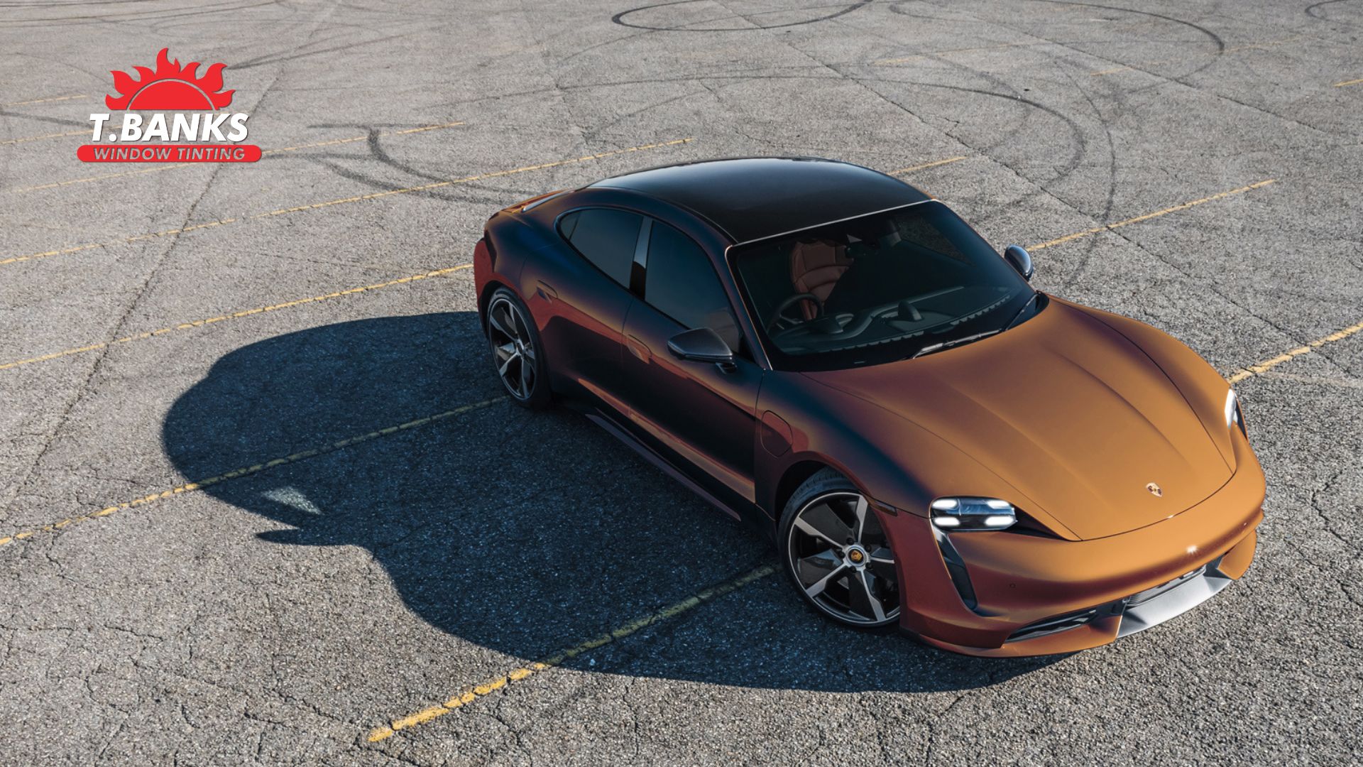 Stylish Porsche parked in an empty lot with professionally installed dark window tint, reflecting the sunset.