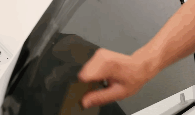 Hand smoothing dark window tint film onto a car window from the inside, pressing out air and moisture for a clean finish. The action shows the final step of window tint application for a sleek and even result.